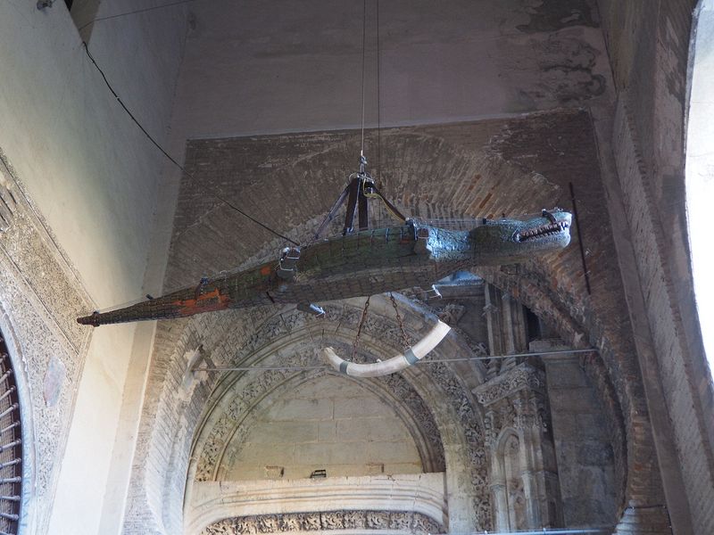 A wooden alligator hangs in the entrance to the cathedral courtyard