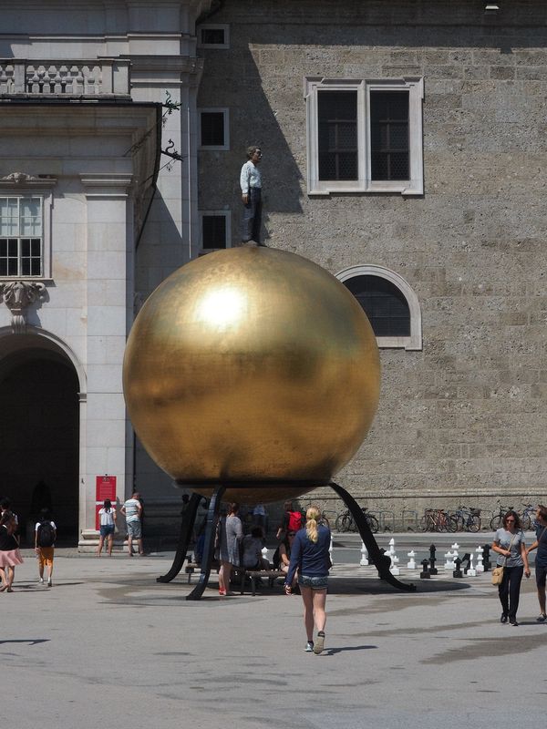 A sculpture of a man on top of a gold ball