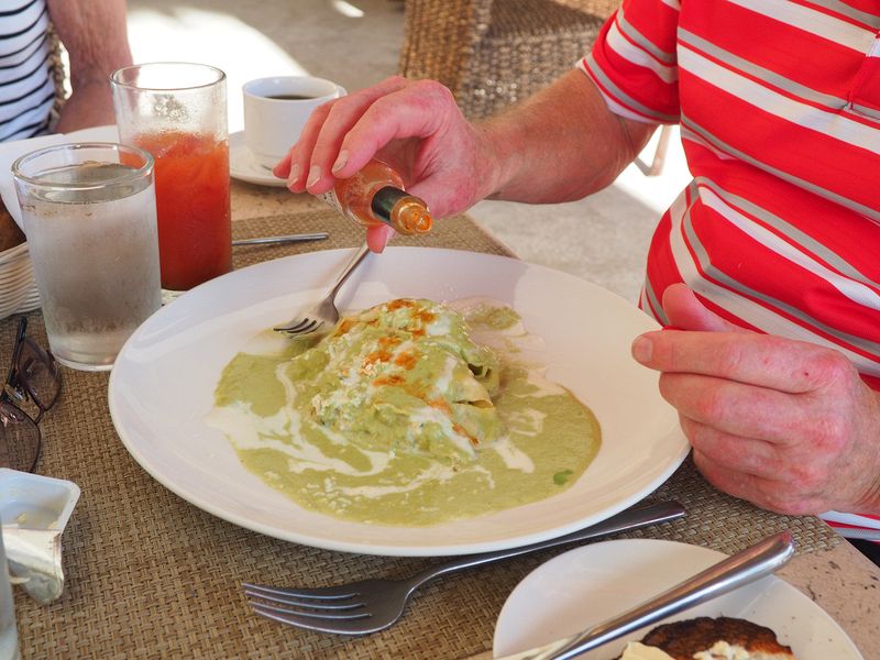 Livingston puts tabasco sauce on his breakfast