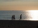 People walk on the beach at sunset