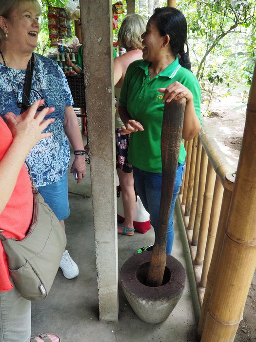 Linda talks to a woman grinding coffee with a mortar and pestle