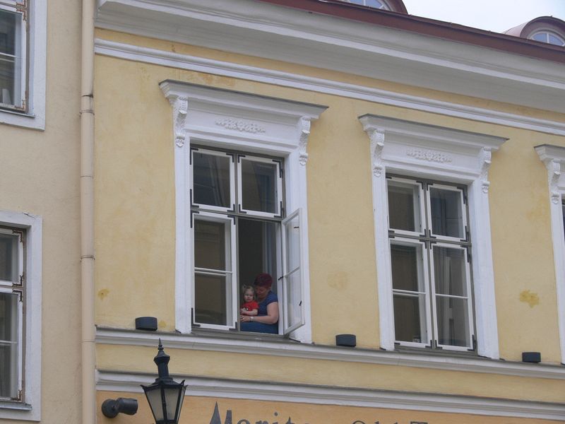 A woman holds a little girl in a window