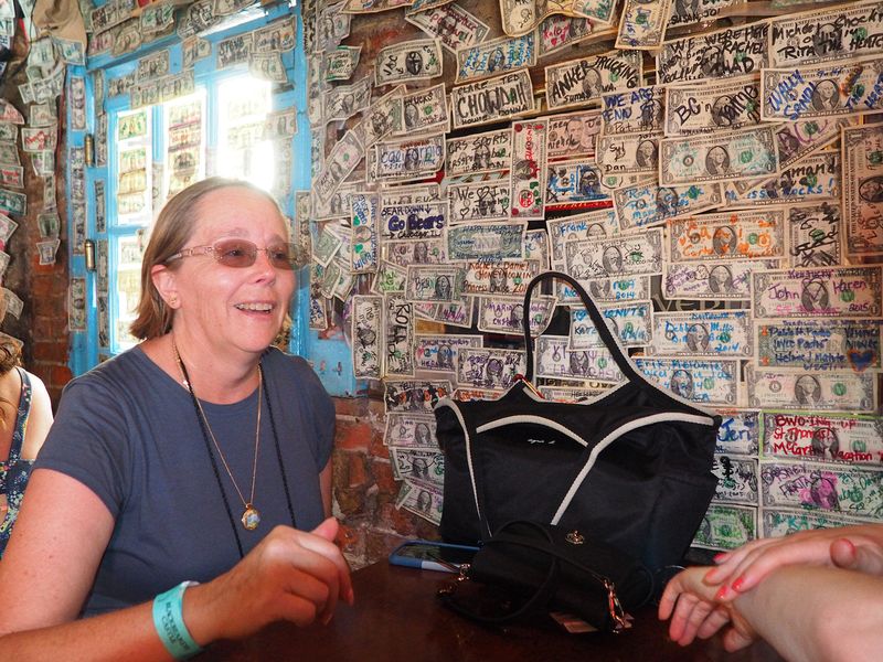 June next to wall covered with $1 bills