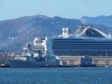 The cruise ship dwarfs this Navy ship