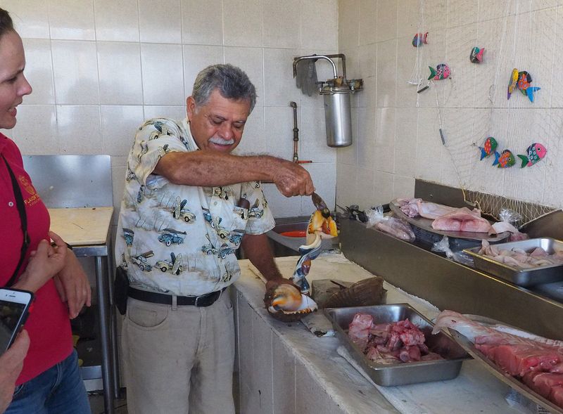 The shop owner pulls a sea snail out of its shell to show us