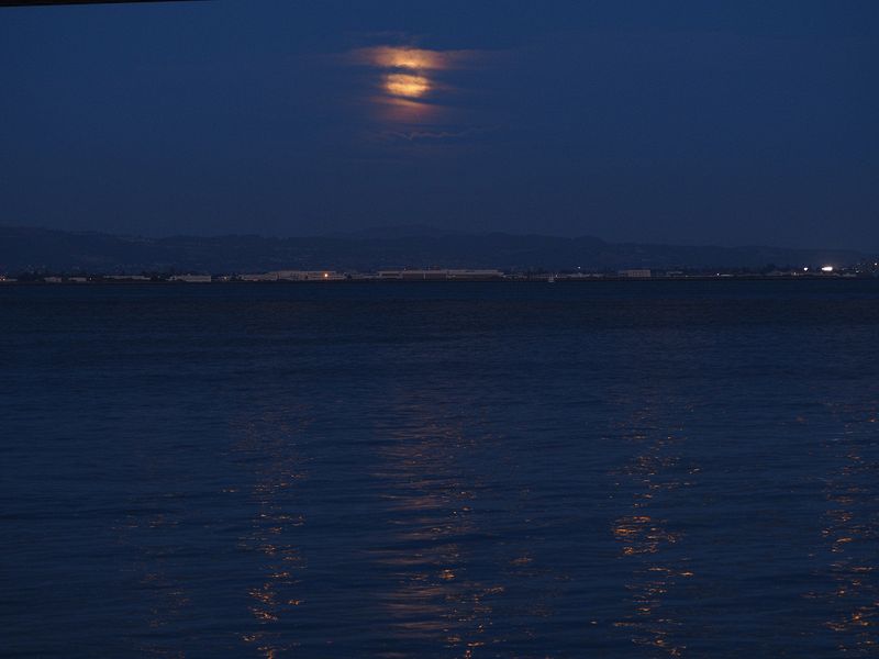 A cloud shrouded moon reflects off the water