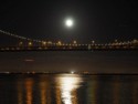 The moon reflects on the water below the Bay Bridge