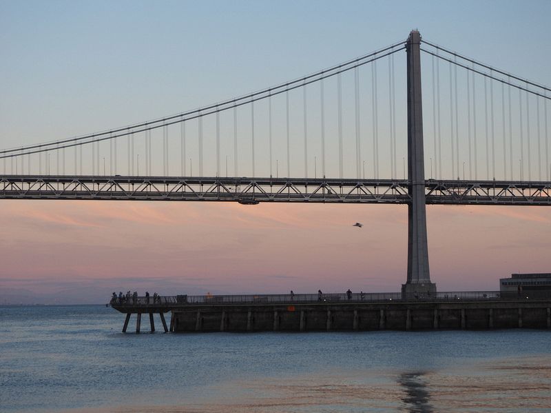 Tourists take pictures of the Bay Bridge from Pier 14