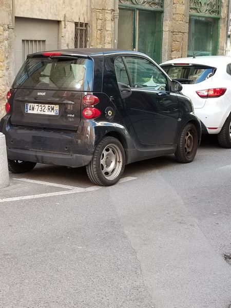 A Smart Car jammed into a tiny parking spot